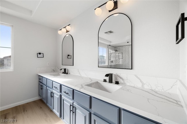 full bath featuring double vanity, visible vents, a sink, and wood finished floors