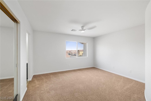 carpeted empty room featuring a ceiling fan, visible vents, and baseboards