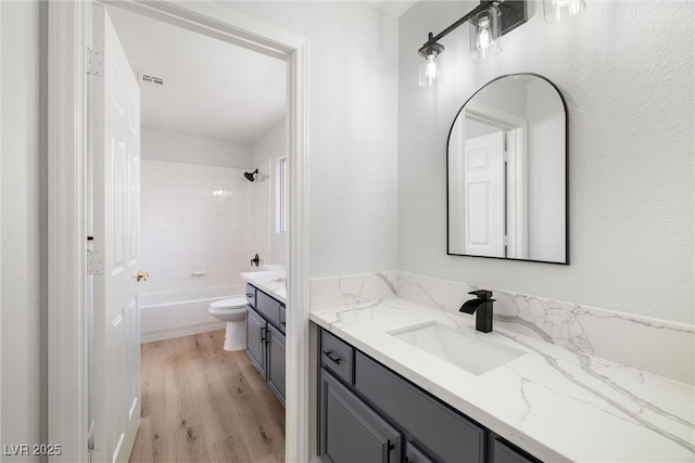 full bath with visible vents, toilet, vanity, shower / tub combination, and wood finished floors