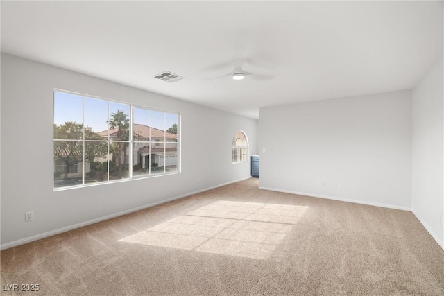 empty room featuring ceiling fan, baseboards, visible vents, and light colored carpet