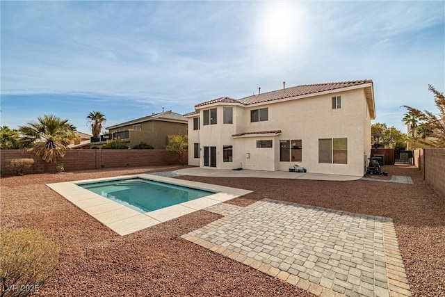 back of house with a fenced in pool, a tile roof, a fenced backyard, a patio area, and stucco siding