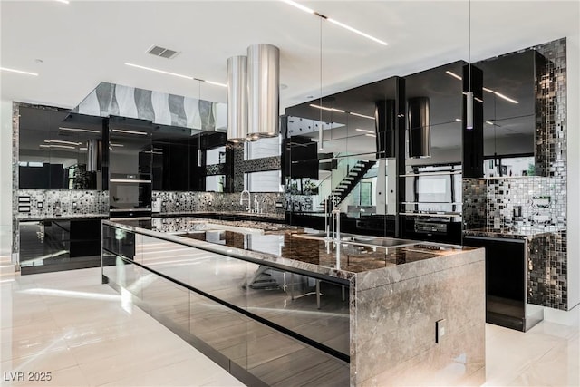 kitchen with dark stone counters, a large island, and backsplash