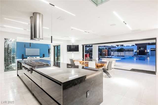 kitchen with light tile patterned flooring, stainless steel gas cooktop, exhaust hood, and a spacious island