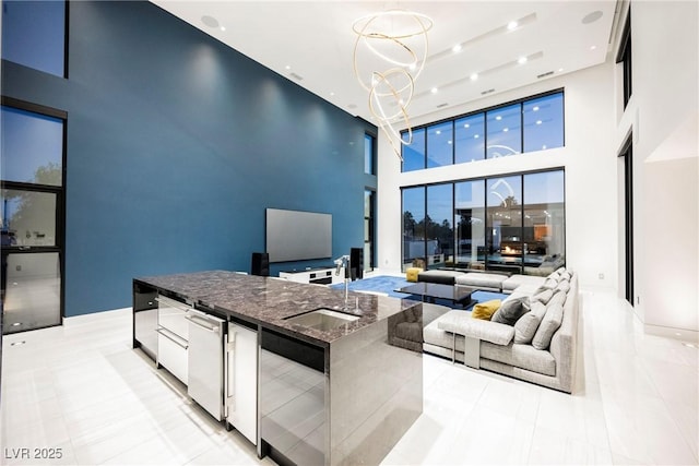 living room with sink, light tile patterned floors, an inviting chandelier, and a towering ceiling