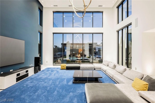 carpeted living room with a high ceiling and an inviting chandelier