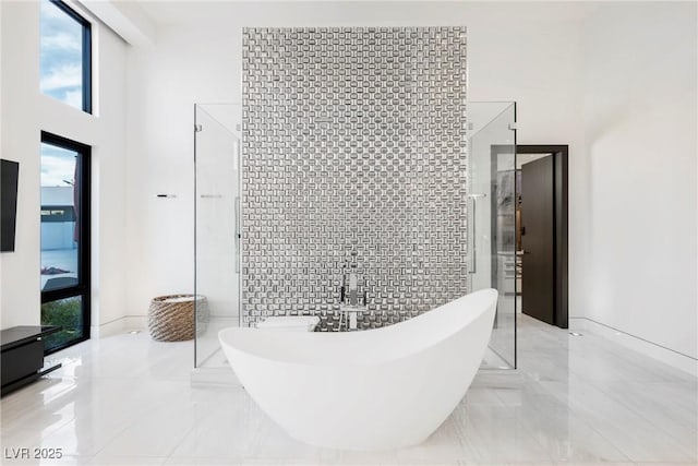 bathroom featuring tile walls, a towering ceiling, and shower with separate bathtub