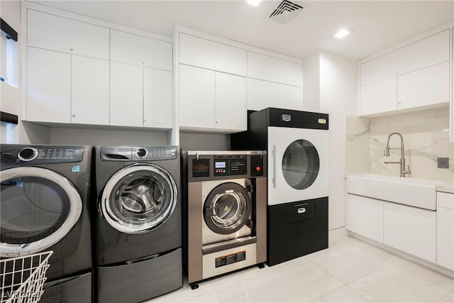 washroom featuring cabinets, sink, washing machine and dryer, and light tile patterned floors