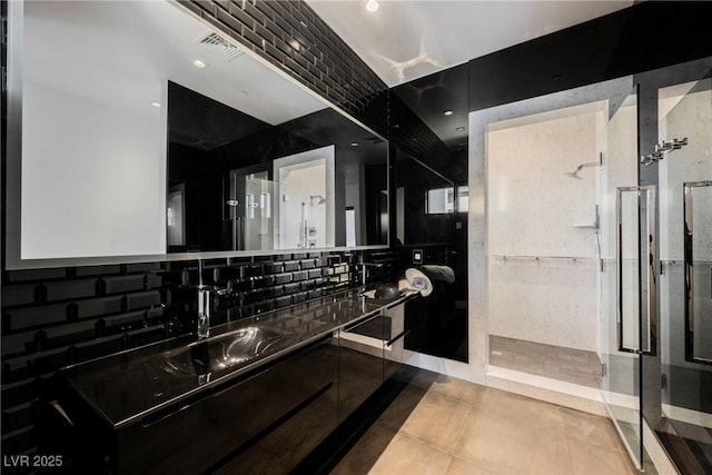 bathroom with vanity, tile patterned flooring, tasteful backsplash, and a tile shower