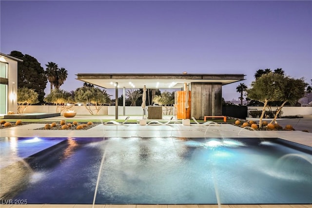 pool at dusk with pool water feature and a patio