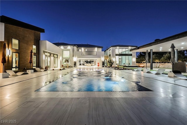 pool at twilight with a patio area