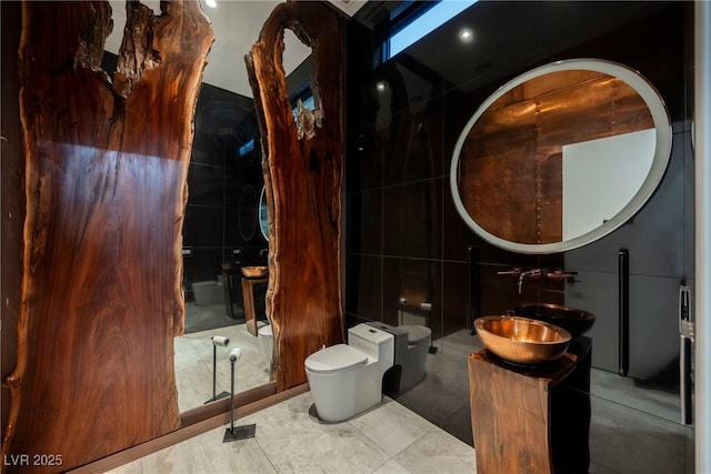 bathroom with vanity, toilet, and tile walls