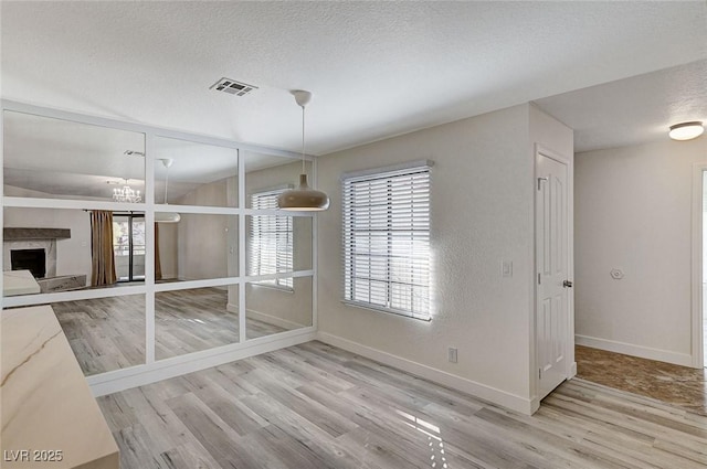 unfurnished dining area with a high end fireplace, wood-type flooring, and a textured ceiling