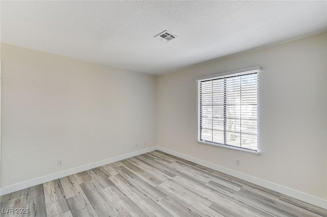 unfurnished room featuring light hardwood / wood-style flooring and a textured ceiling