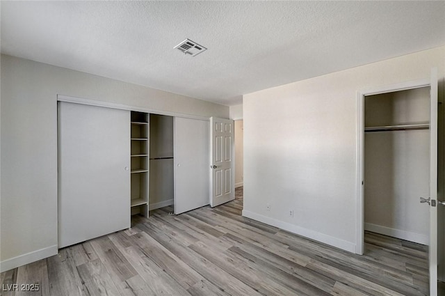 unfurnished bedroom with a textured ceiling and light hardwood / wood-style flooring