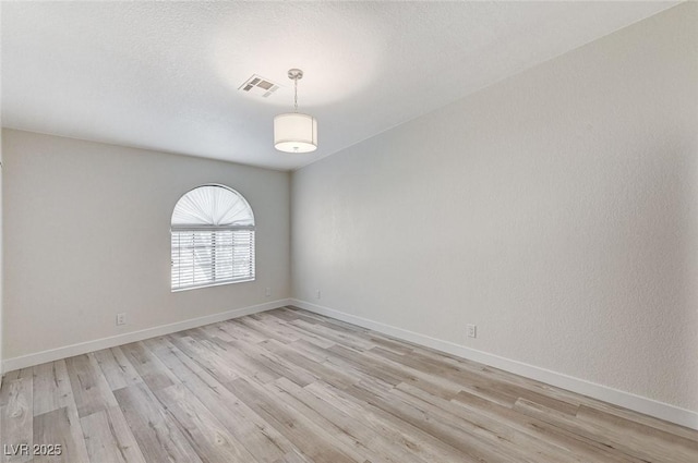 spare room featuring a textured ceiling and light hardwood / wood-style flooring