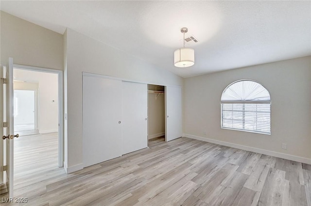 unfurnished bedroom featuring lofted ceiling, light hardwood / wood-style floors, and a closet