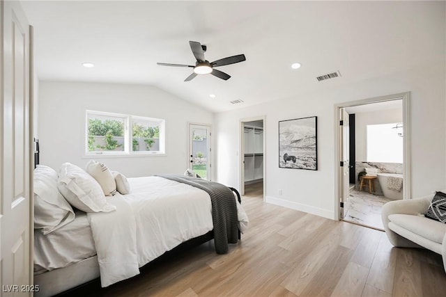 bedroom with vaulted ceiling, ensuite bathroom, a walk in closet, ceiling fan, and light hardwood / wood-style floors