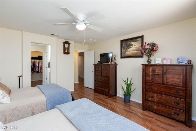 bedroom with dark wood-type flooring, ceiling fan, and a spacious closet