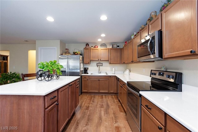 kitchen with stainless steel appliances, sink, a kitchen breakfast bar, and light hardwood / wood-style floors