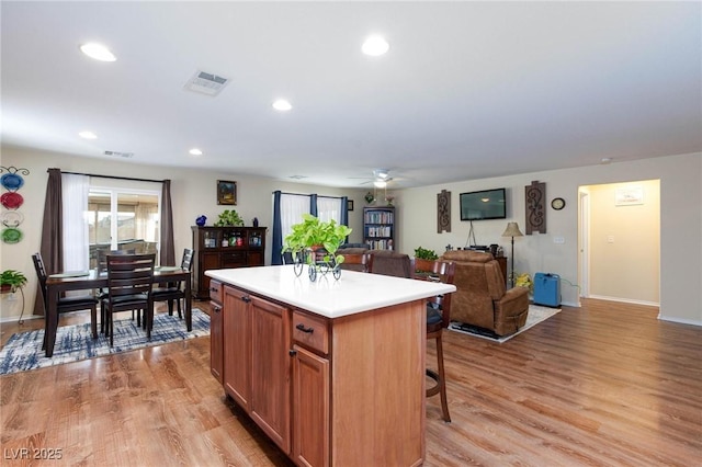 kitchen with light hardwood / wood-style flooring, a breakfast bar, ceiling fan, and a kitchen island