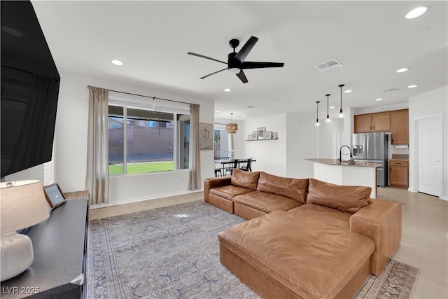 living room with sink, ceiling fan, and light hardwood / wood-style flooring