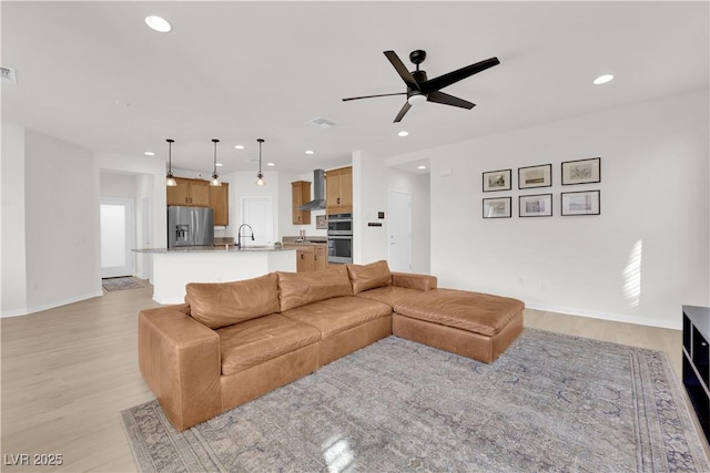 living room with sink, ceiling fan, and light wood-type flooring