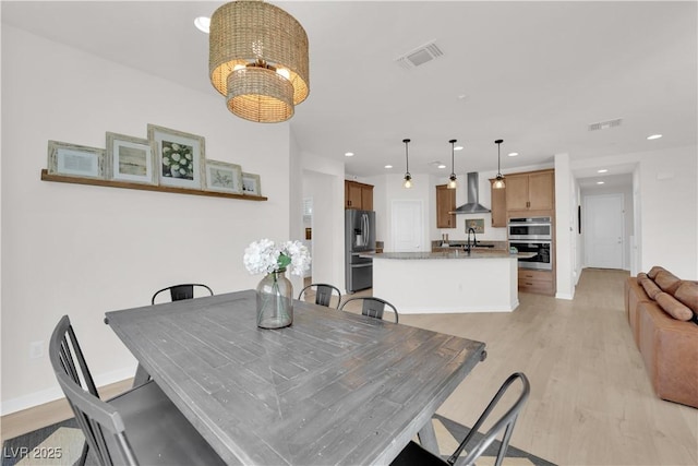 dining area with a chandelier, sink, and light hardwood / wood-style flooring