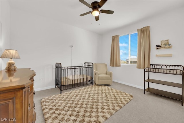 bedroom with a crib, light carpet, and ceiling fan