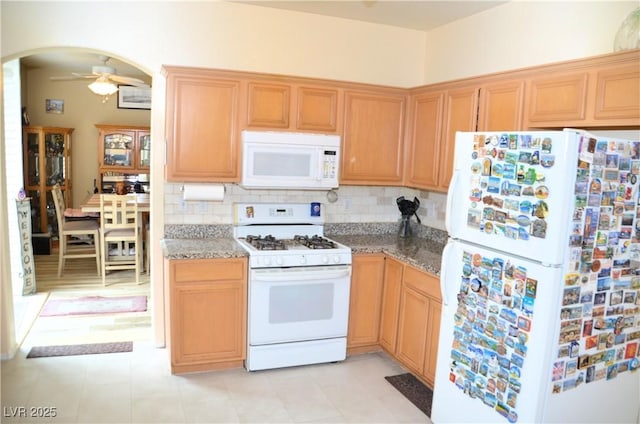 kitchen with ceiling fan, white appliances, dark stone counters, and tasteful backsplash