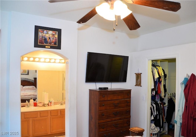 bedroom with ceiling fan, ensuite bath, and sink