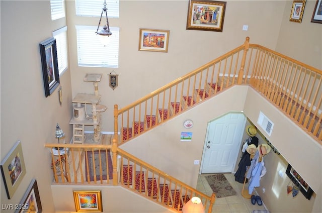 stairs with tile patterned floors and a high ceiling