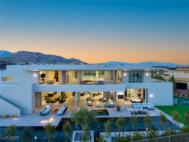 back house at dusk with an outdoor living space and a mountain view