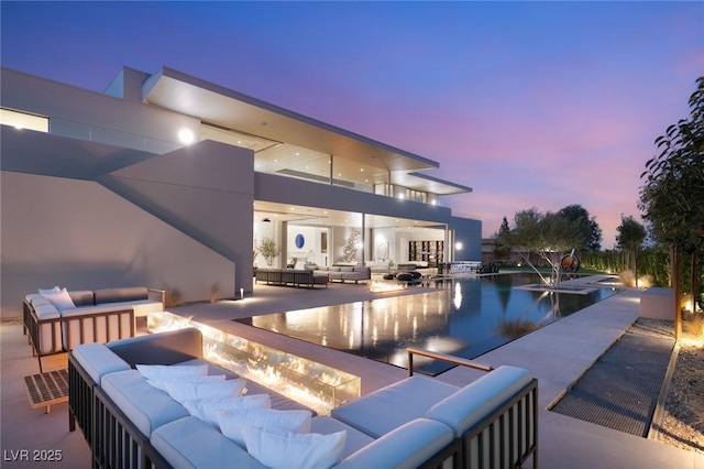 pool at dusk with an outdoor living space and a patio area