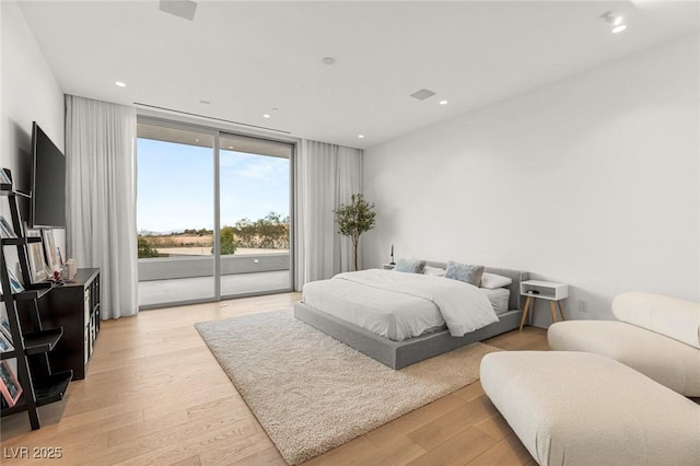 bedroom with access to exterior, a wall of windows, and light hardwood / wood-style floors