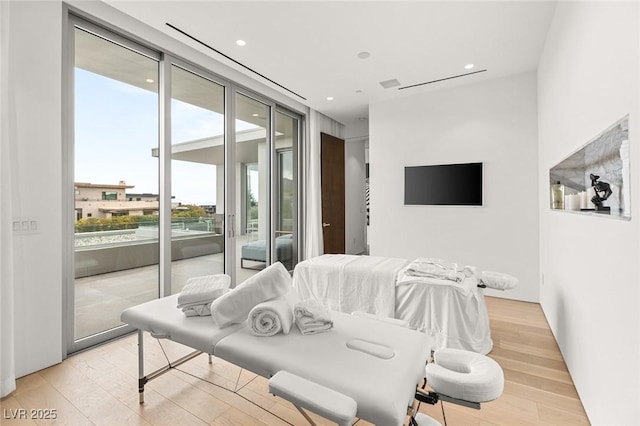 bedroom featuring access to exterior, a wall of windows, and light hardwood / wood-style floors