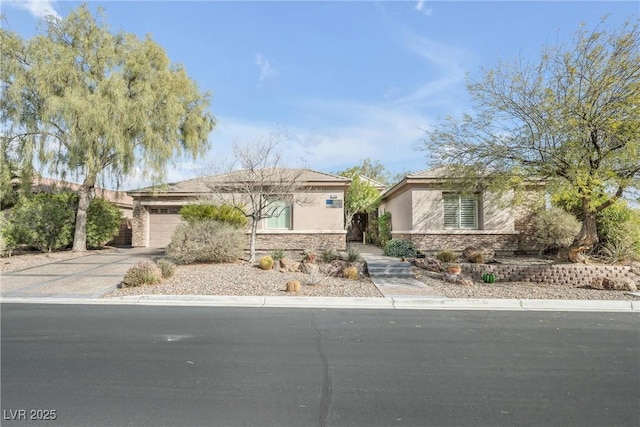 view of front of property featuring an attached garage, stone siding, concrete driveway, and stucco siding