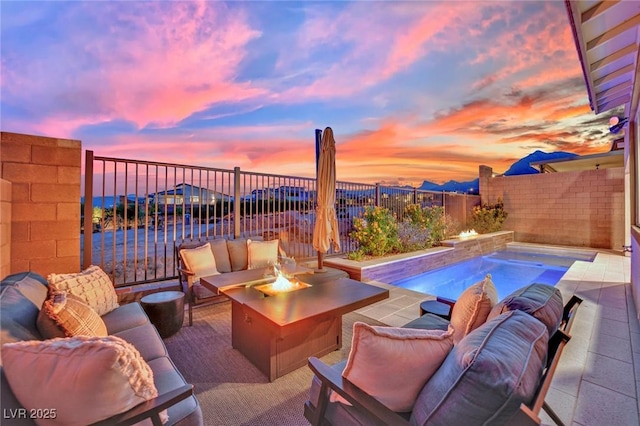 patio terrace at dusk featuring a fenced in pool and an outdoor living space with a fire pit