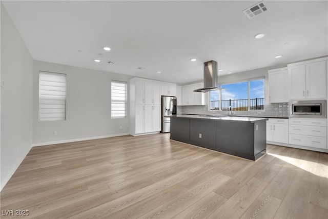 kitchen featuring white cabinetry, stainless steel appliances, tasteful backsplash, island range hood, and a kitchen island