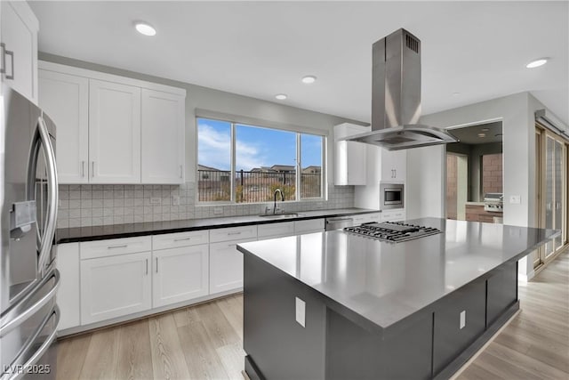 kitchen with sink, appliances with stainless steel finishes, island exhaust hood, light hardwood / wood-style floors, and white cabinets