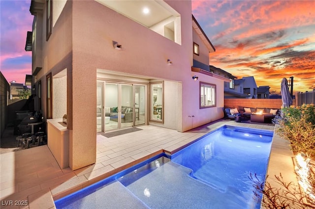 pool at dusk with an outdoor fire pit and a patio area