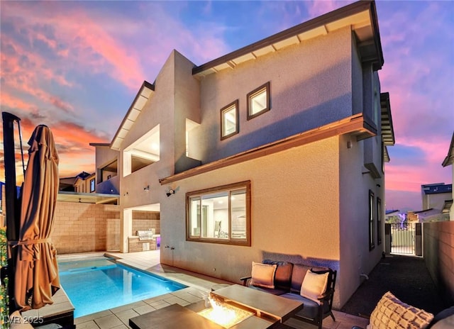 back house at dusk with a fenced in pool, a patio area, and an outdoor fire pit