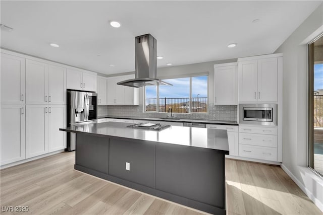 kitchen featuring light hardwood / wood-style flooring, appliances with stainless steel finishes, white cabinetry, island range hood, and a kitchen island