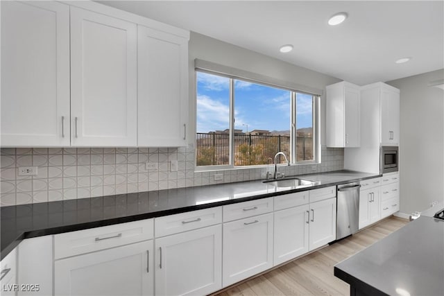 kitchen featuring white cabinetry, sink, stainless steel appliances, and light wood-type flooring