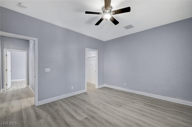 empty room with a ceiling fan, baseboards, visible vents, and wood finished floors