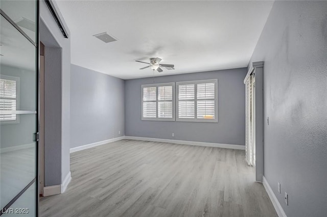 unfurnished bedroom with multiple windows, wood finished floors, and visible vents