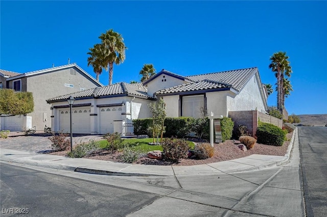 view of front of home with driveway, a tiled roof, an attached garage, fence, and stucco siding