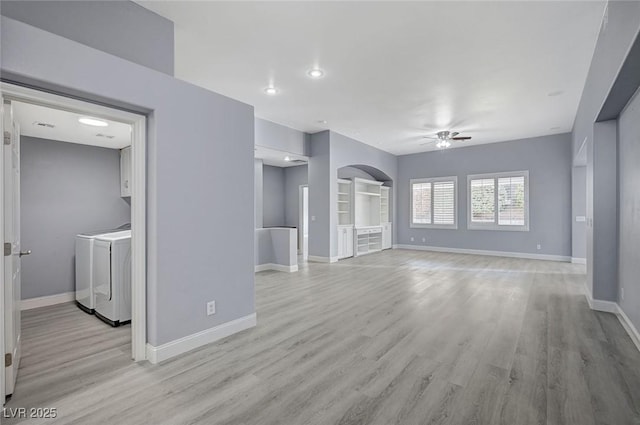 unfurnished living room with ceiling fan, baseboards, washing machine and dryer, and light wood-style floors