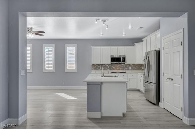 kitchen with a sink, visible vents, baseboards, appliances with stainless steel finishes, and backsplash