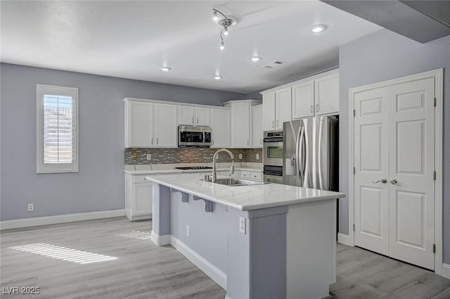 kitchen featuring white cabinetry, appliances with stainless steel finishes, decorative backsplash, and a sink