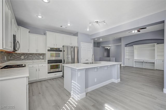 kitchen featuring stainless steel appliances, visible vents, white cabinetry, a sink, and light wood-type flooring